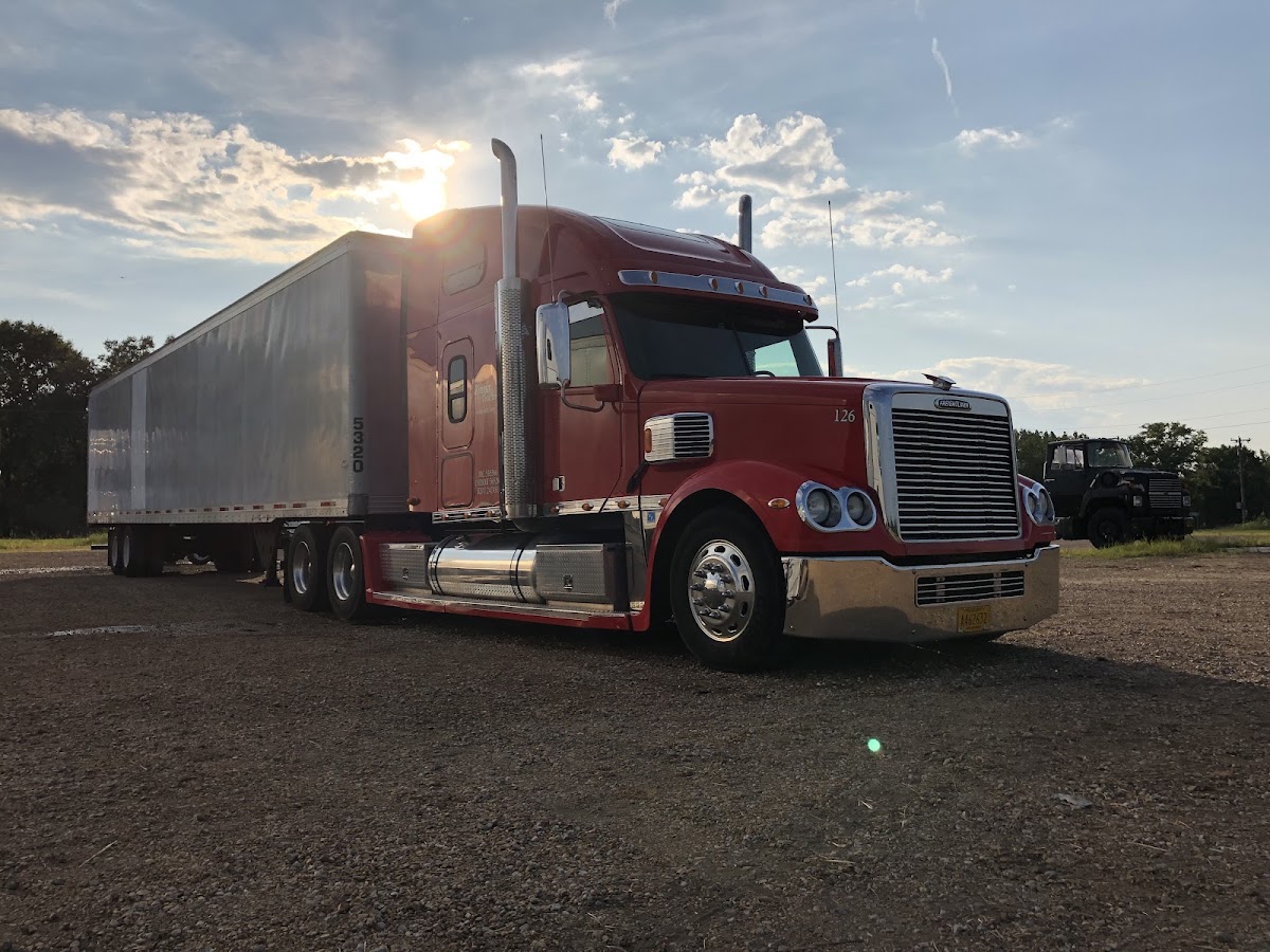 Red semi truck and trailer washed and gleaming at sunrise