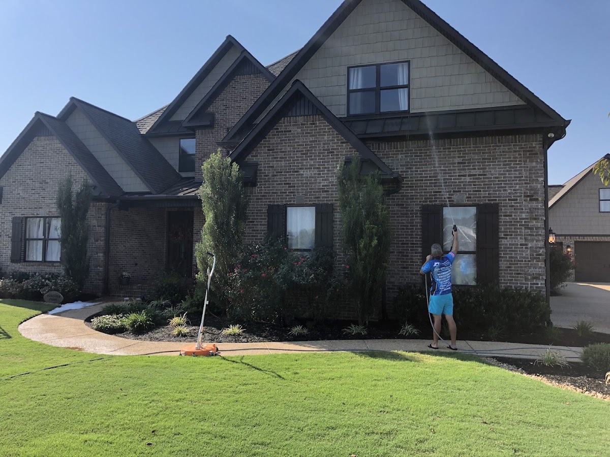 Precision crew member soft washing the brick front of a two storey house